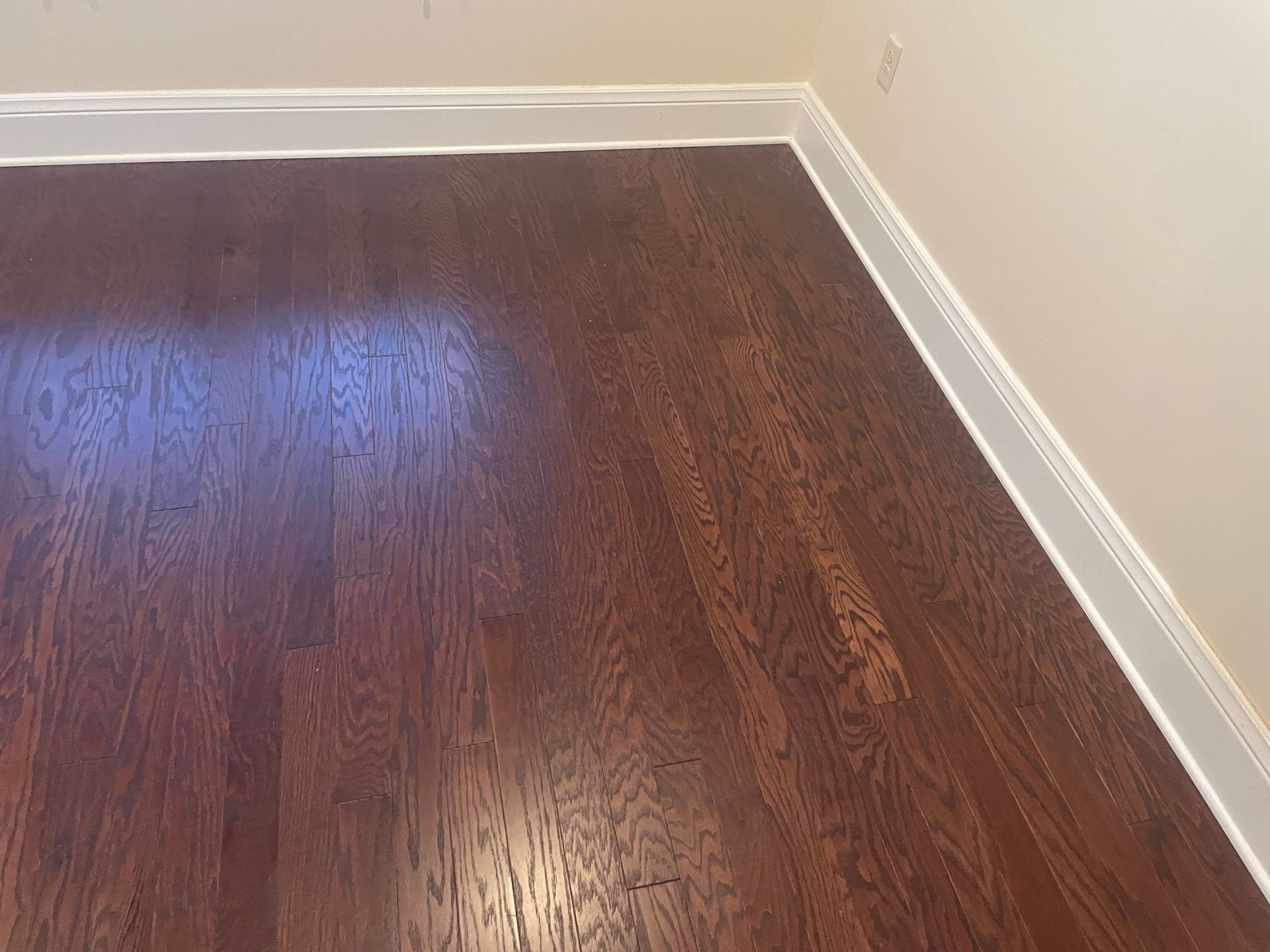A close up of a wooden floor in a room with white trim.