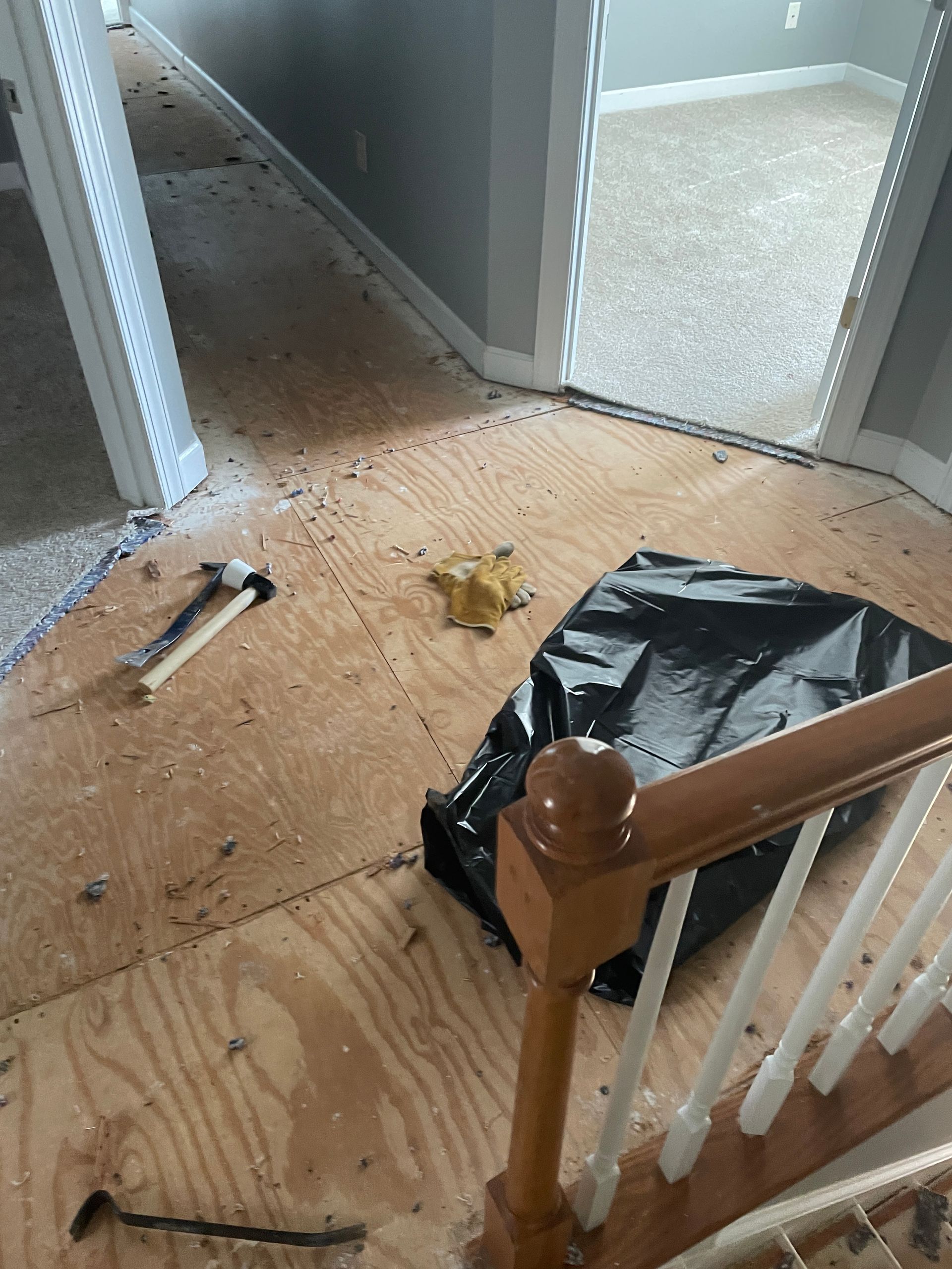 A hammer is laying on the floor next to a staircase.