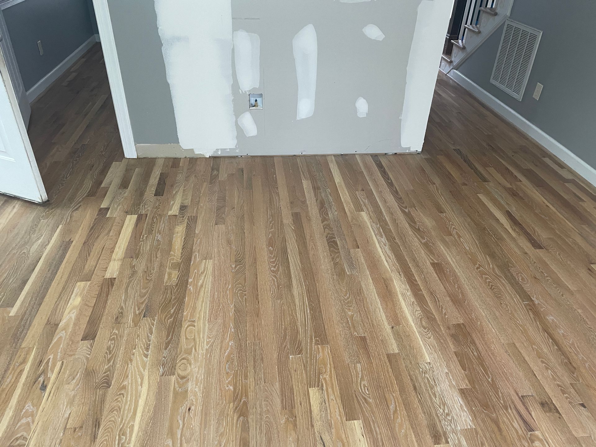 A wooden floor in a room with a door in the background.
