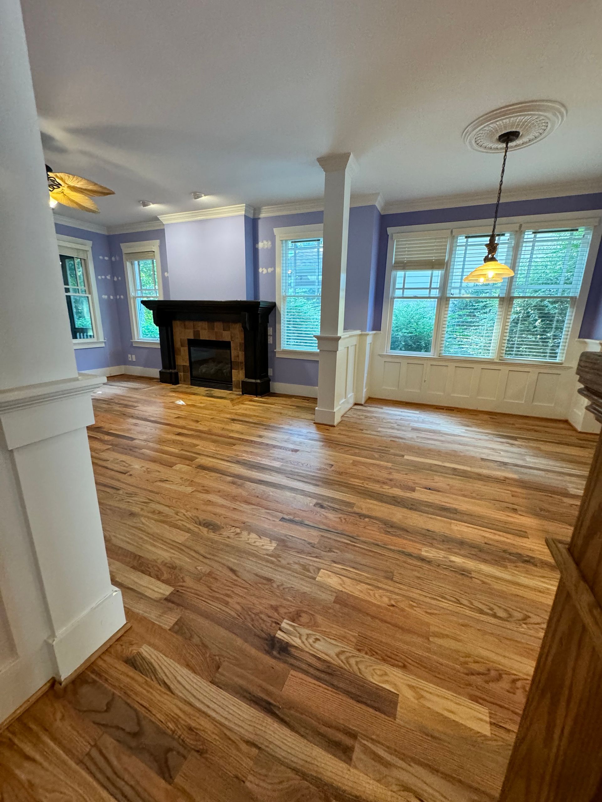 An empty living room with hardwood floors and a fireplace.