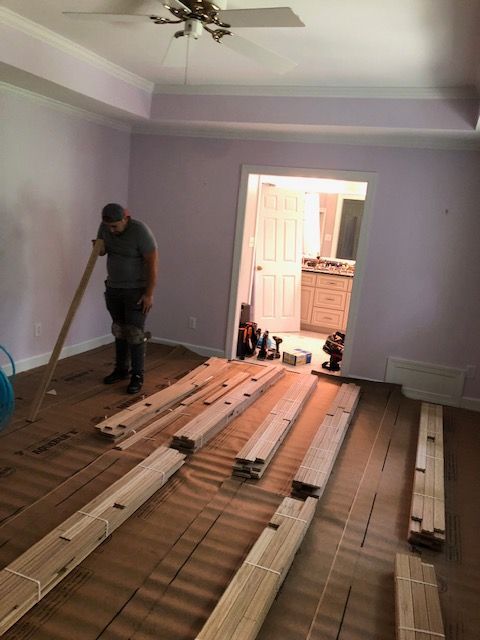 A man is installing a wooden floor in a room.
