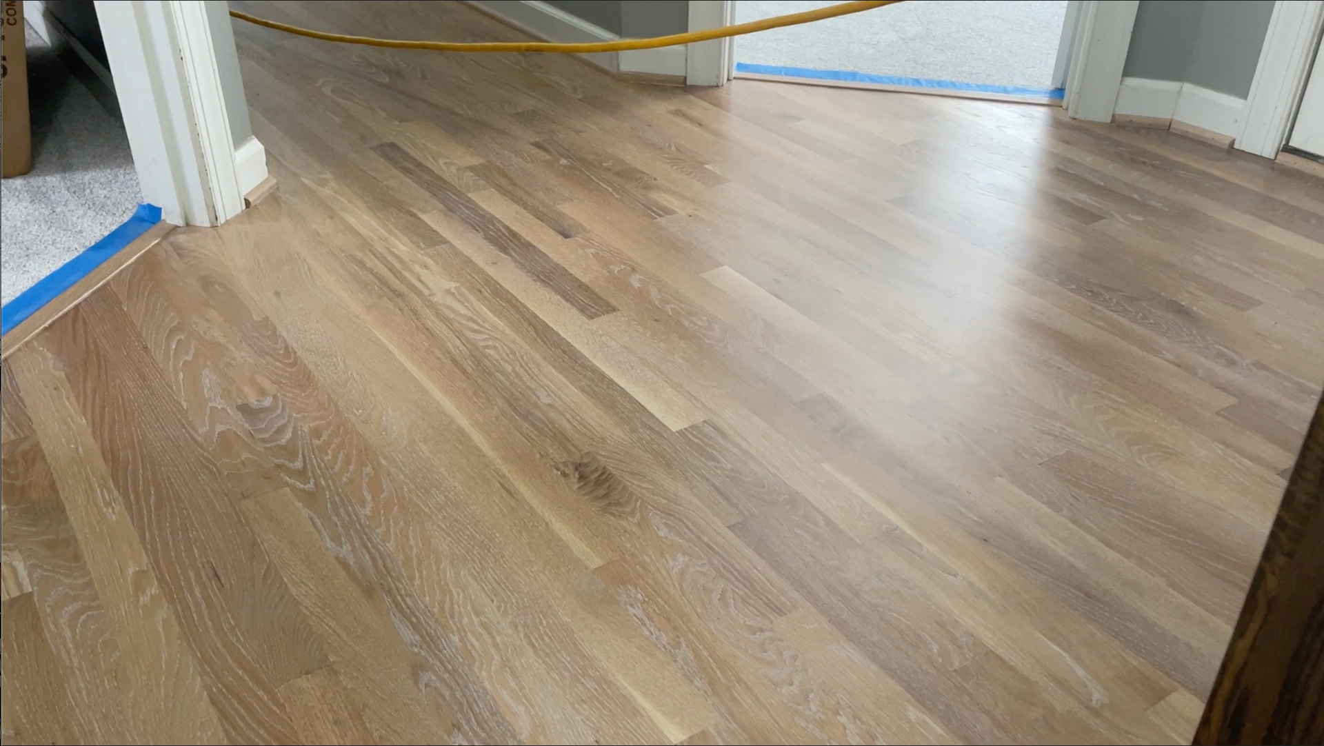 A wooden floor in a room with a door in the background.