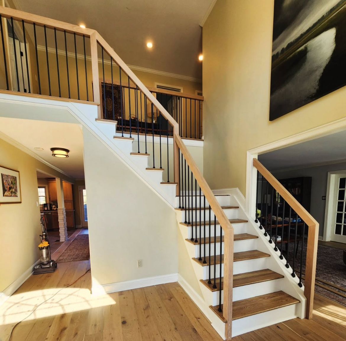 Staircase in a home with wooden steps and railing. Black metal spindles. Stair installation company Raleigh NC.