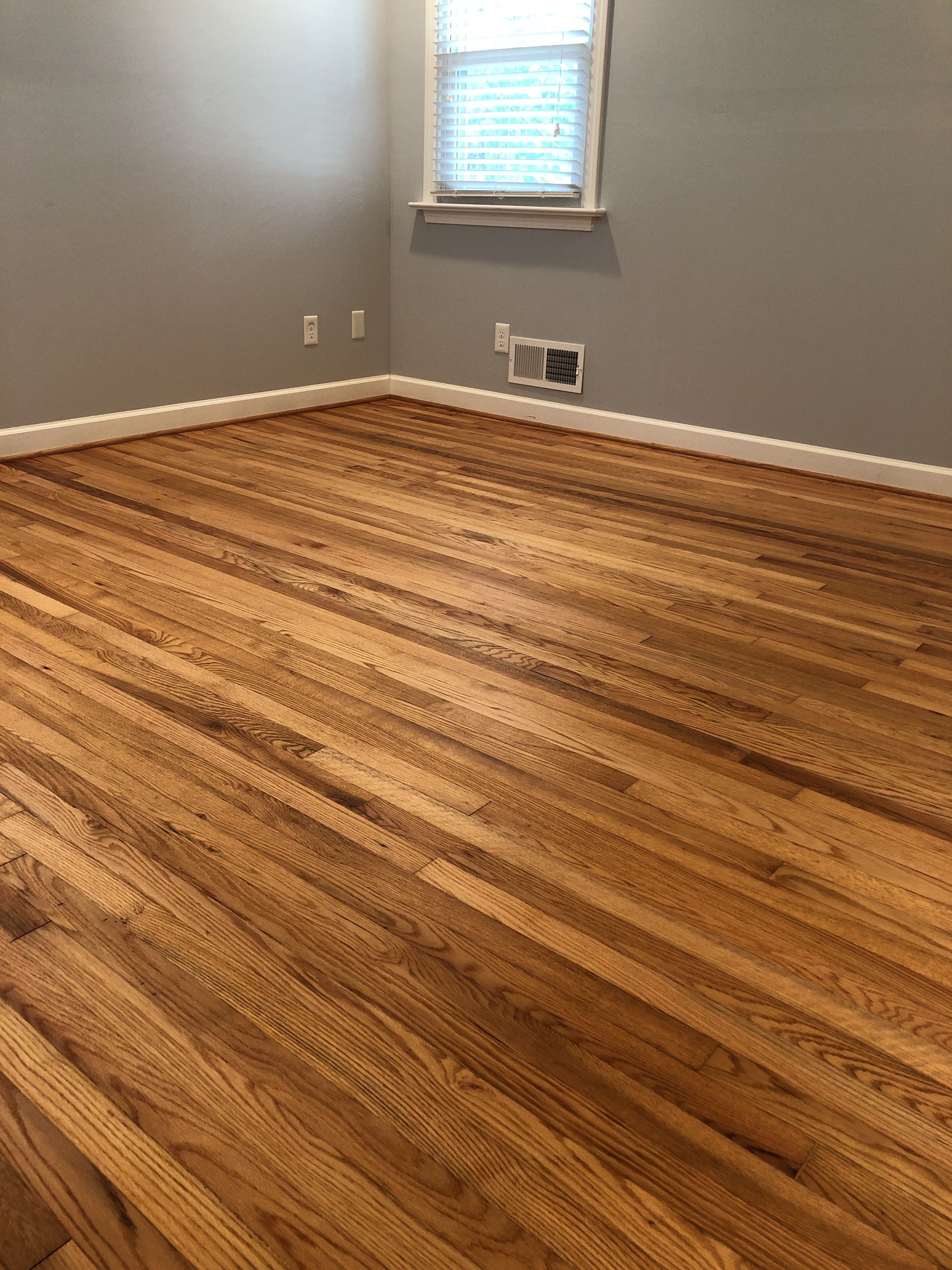 An empty room with hardwood floors and a window.