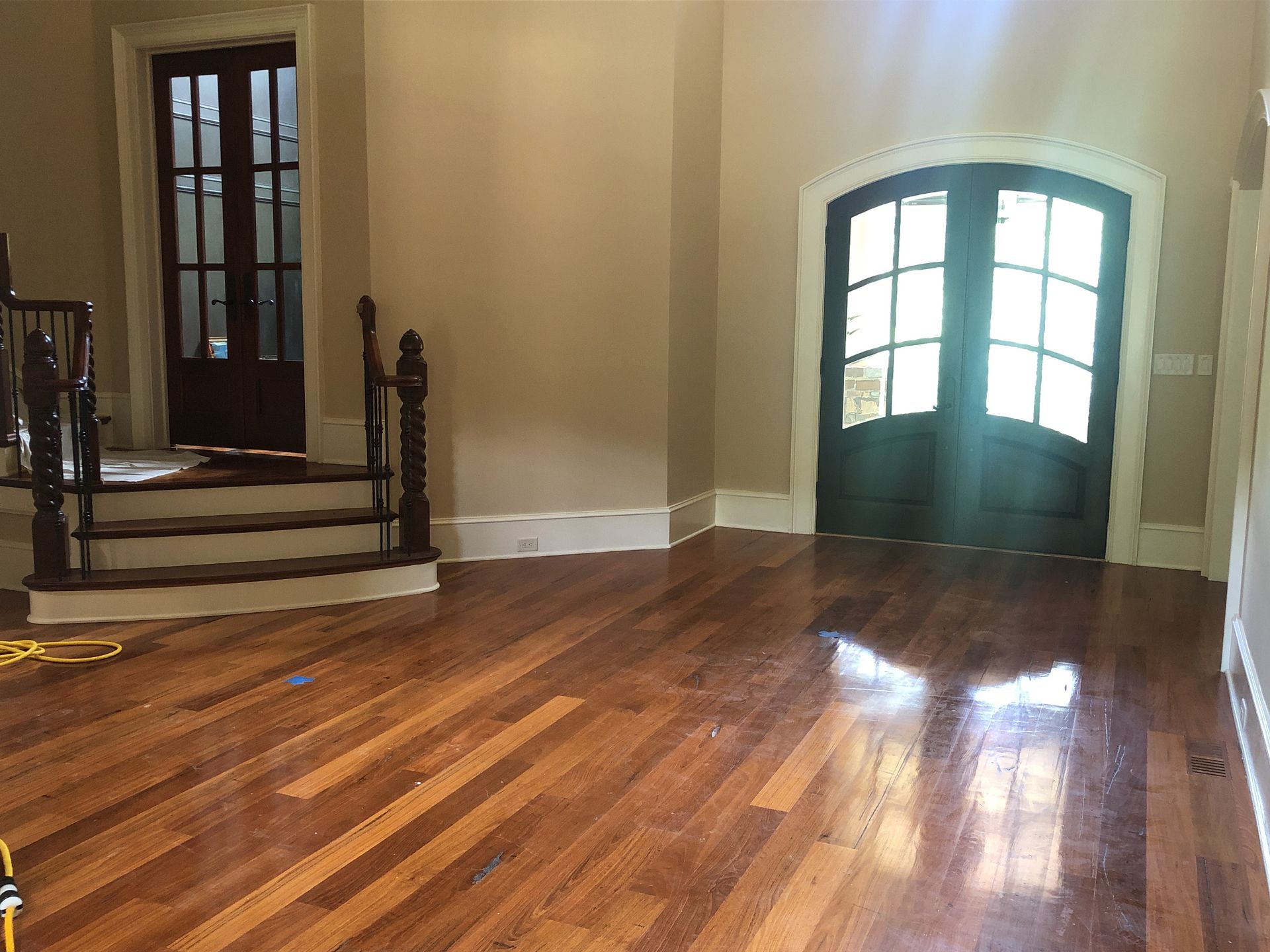 An empty room with hardwood floors and stairs in a house.