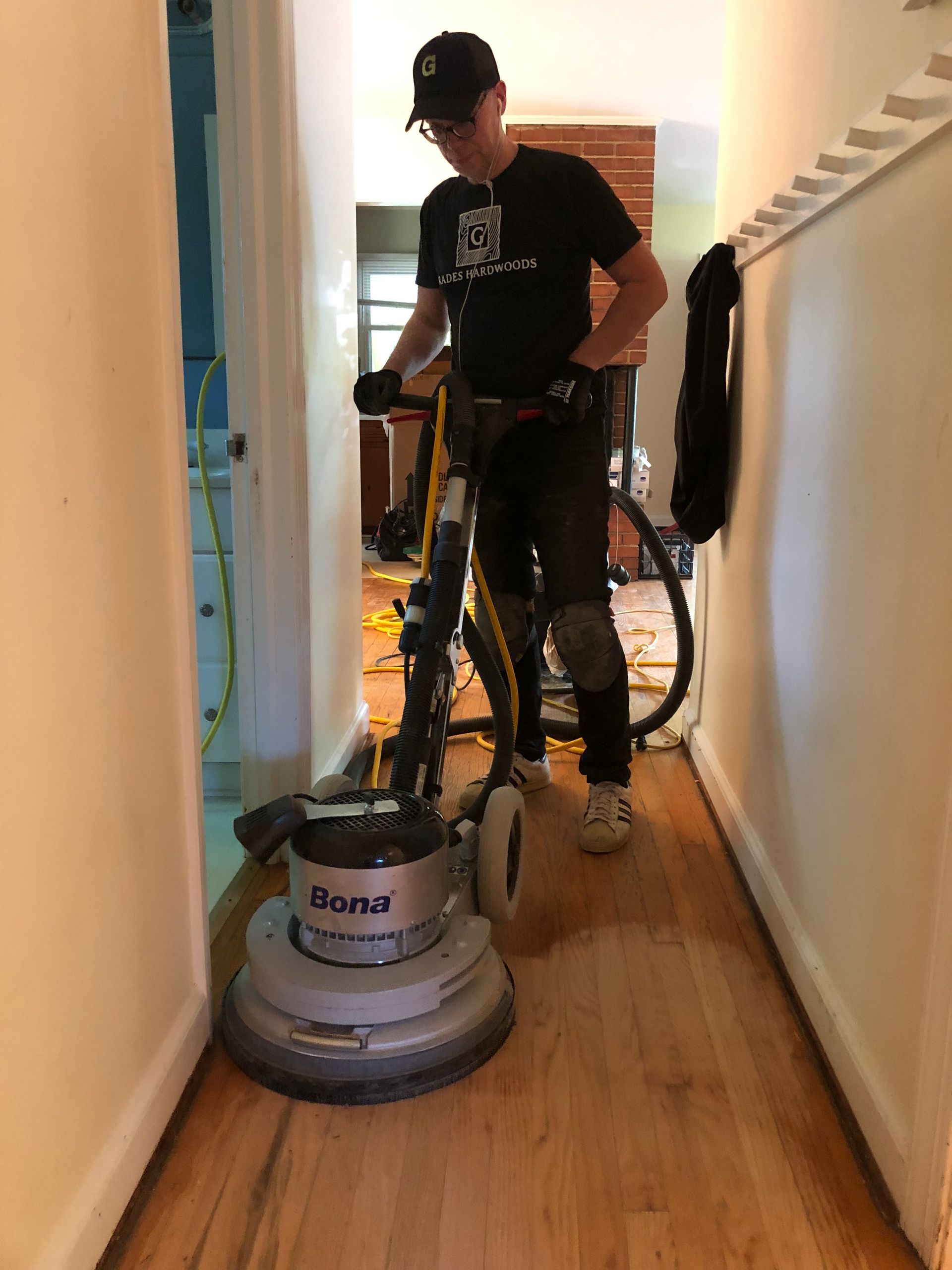 Person sanding wooden floor in hallway with a floor sander.