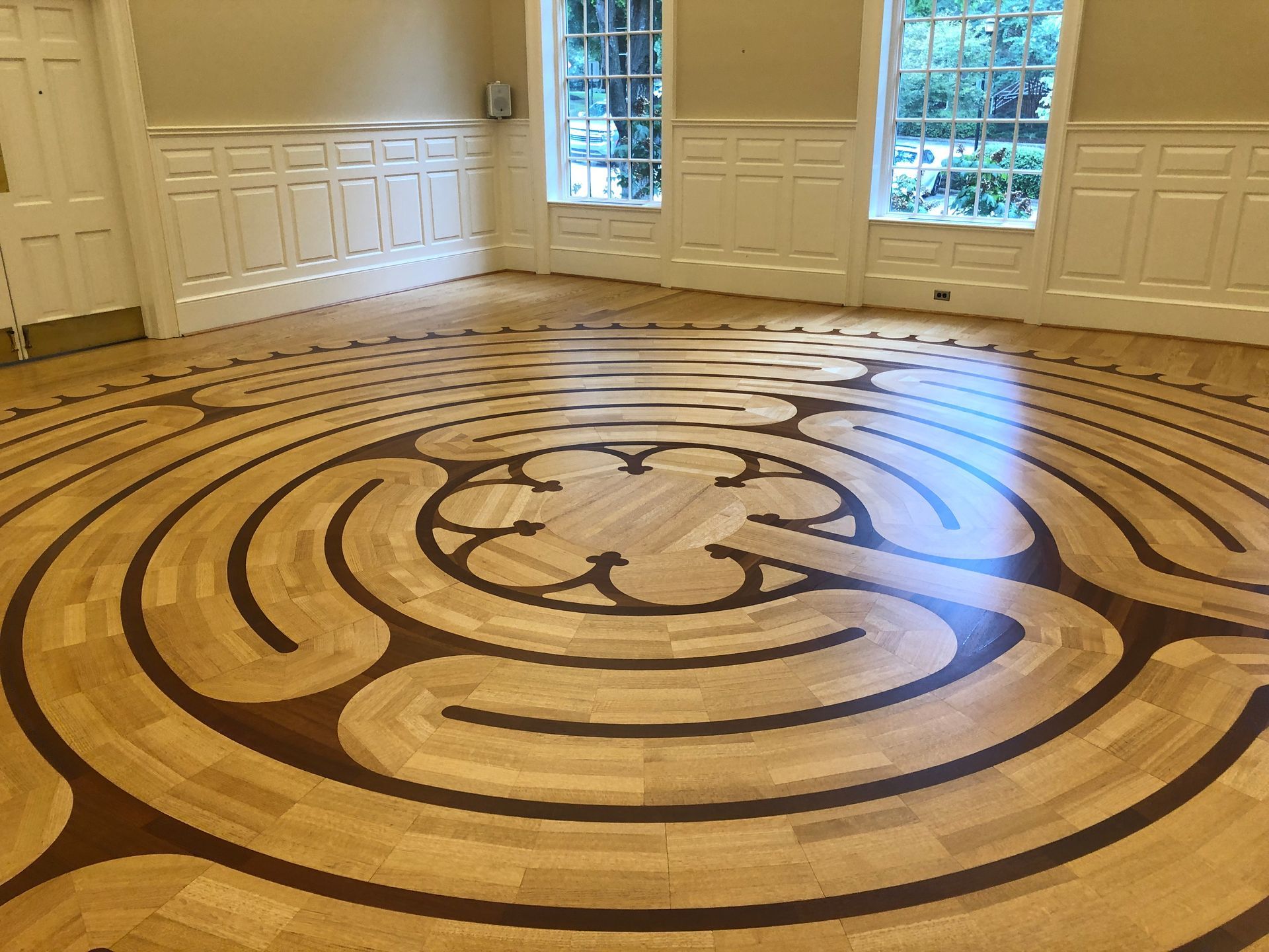 Wooden floor labyrinth in a room with white walls and windows.