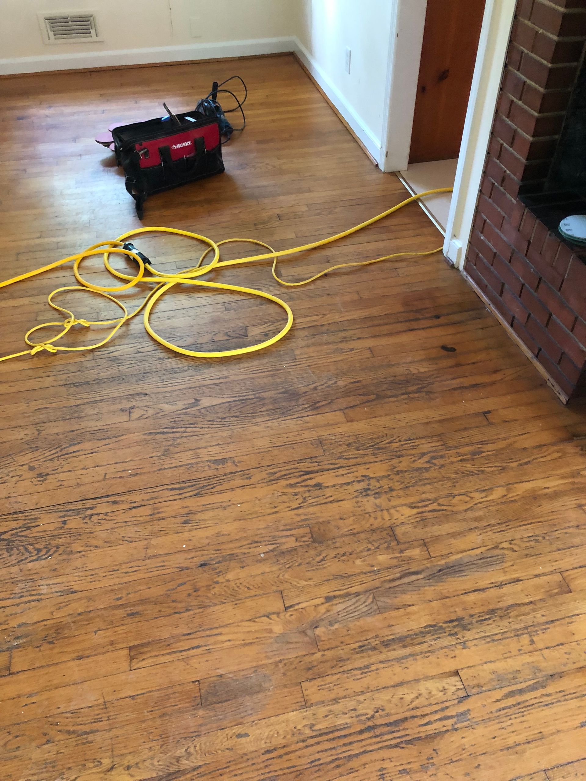 Hardwood floor with power tool and yellow extension cord.
