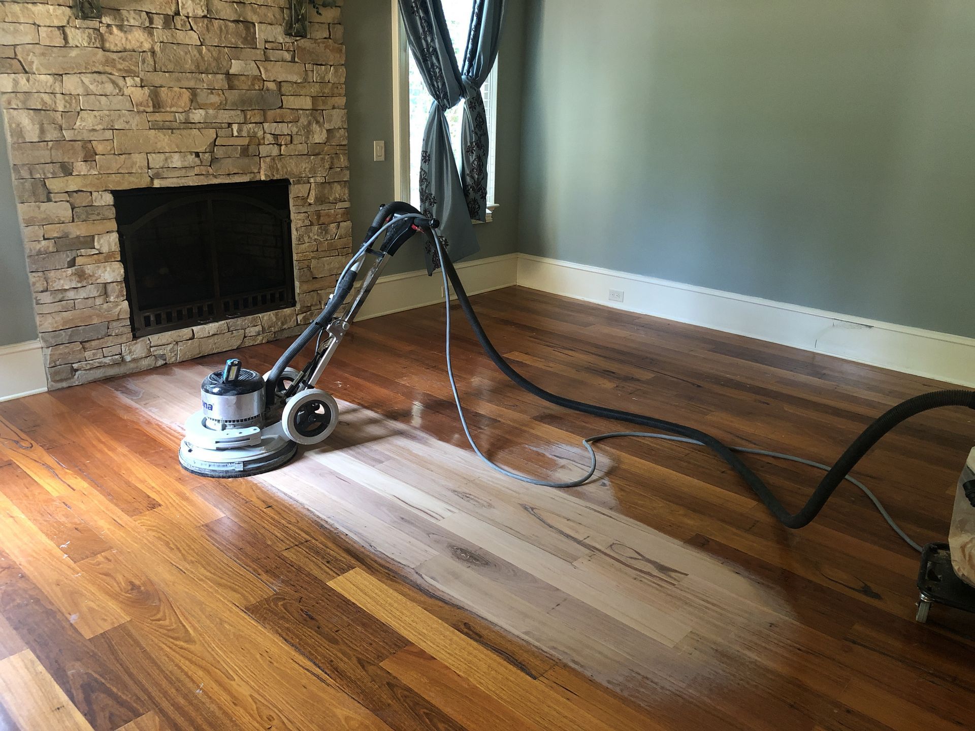 Sanding a wooden floor in a bedroom in Raleigh NC.