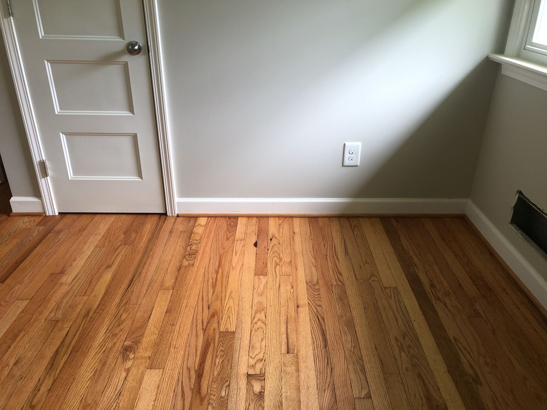 A room with natural oil finished hardwood floors and a white door