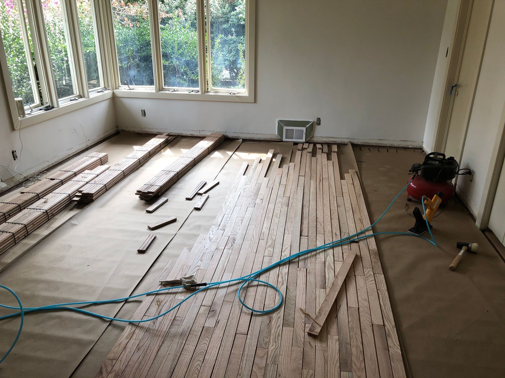 A wooden floor is being installed in a room with a window.