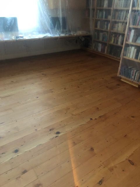 A room with a wooden floor and a bookshelf filled with books.