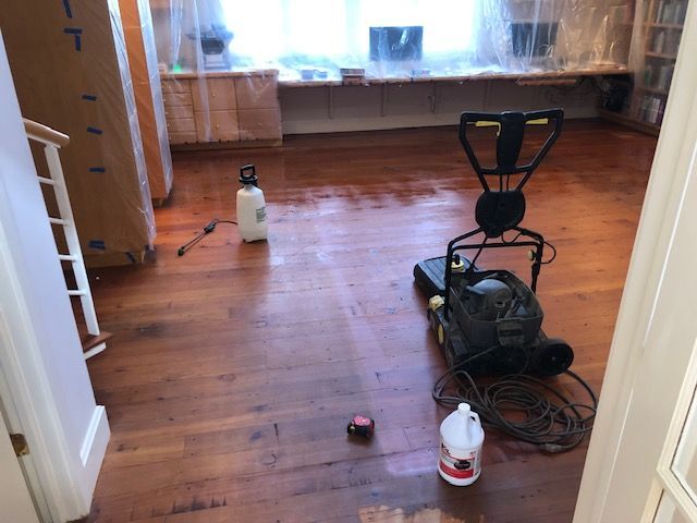 A floor cleaning machine is sitting on a wooden floor in a room.