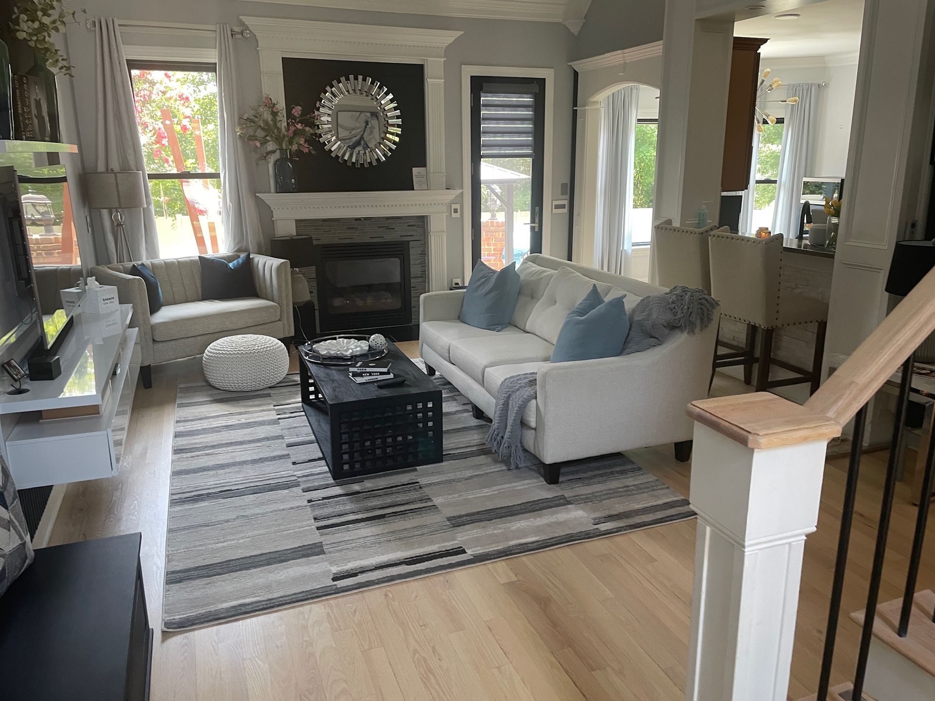 Living room with light-colored sofas, fireplace, area rug, and hardwood floors refinished in Cary NC.