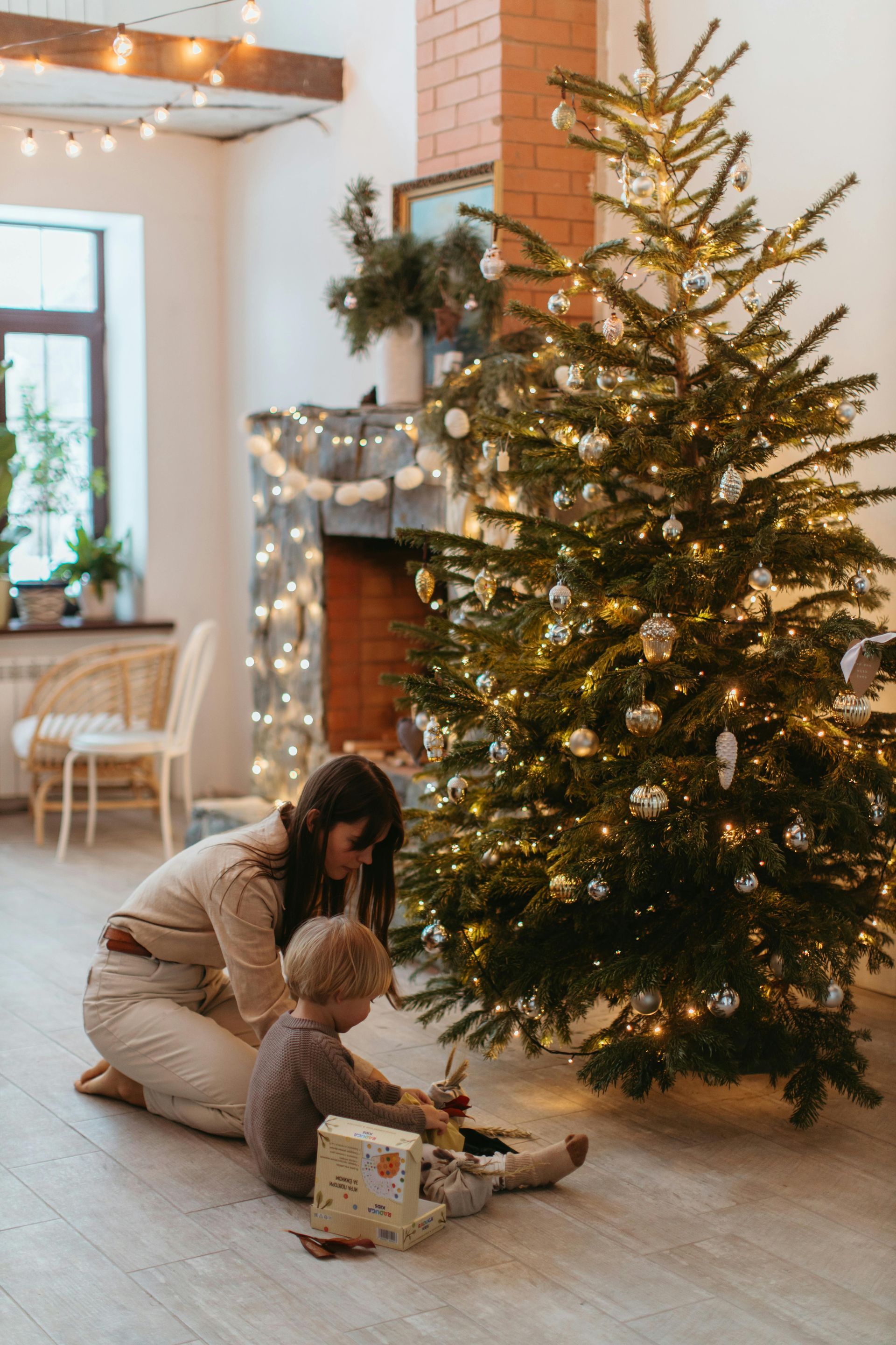 A woman and a child are decorating a christmas tree in a living room.