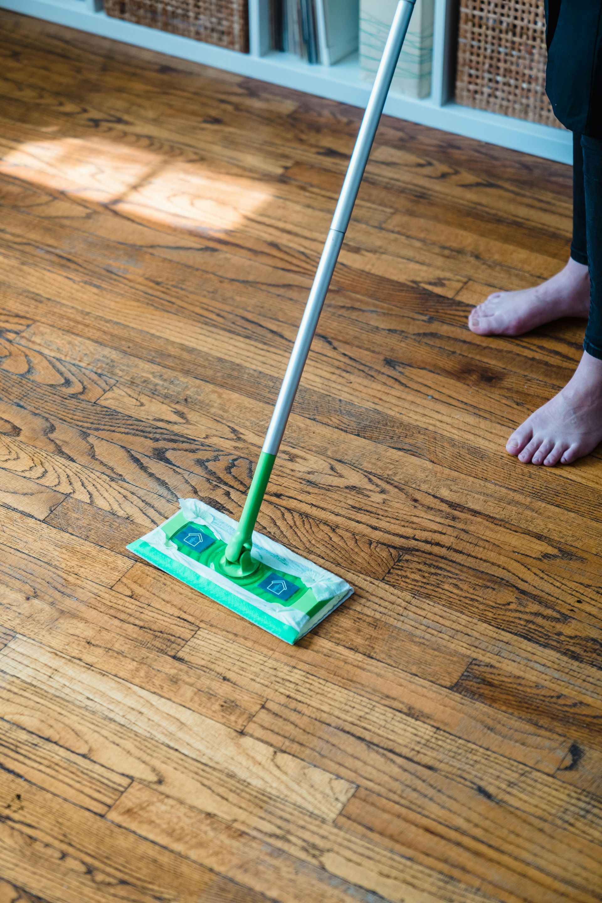 A person is cleaning a wooden floor with a mop.