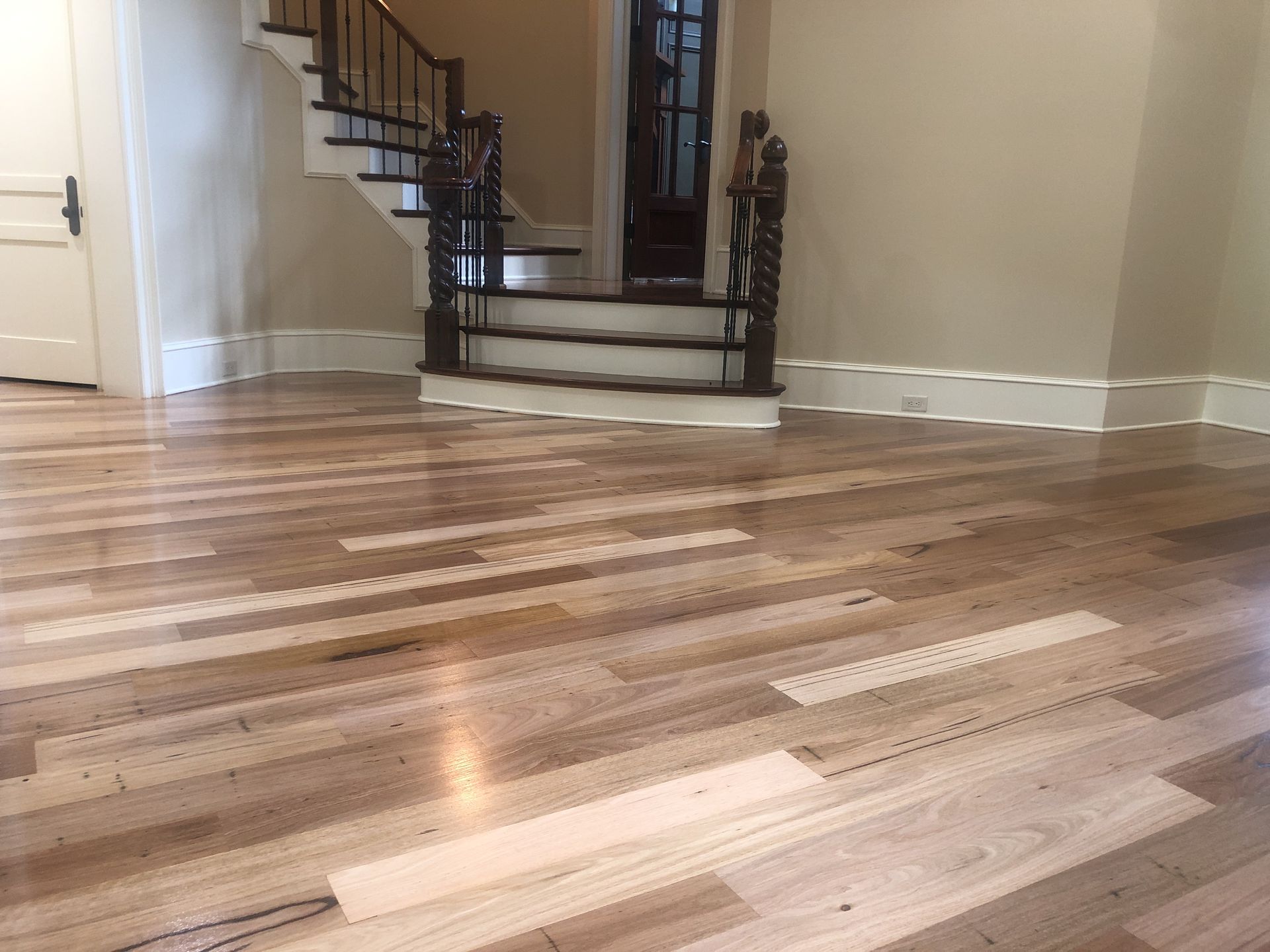 Wooden floor in a home with a staircase. Cream-colored walls and white trim.