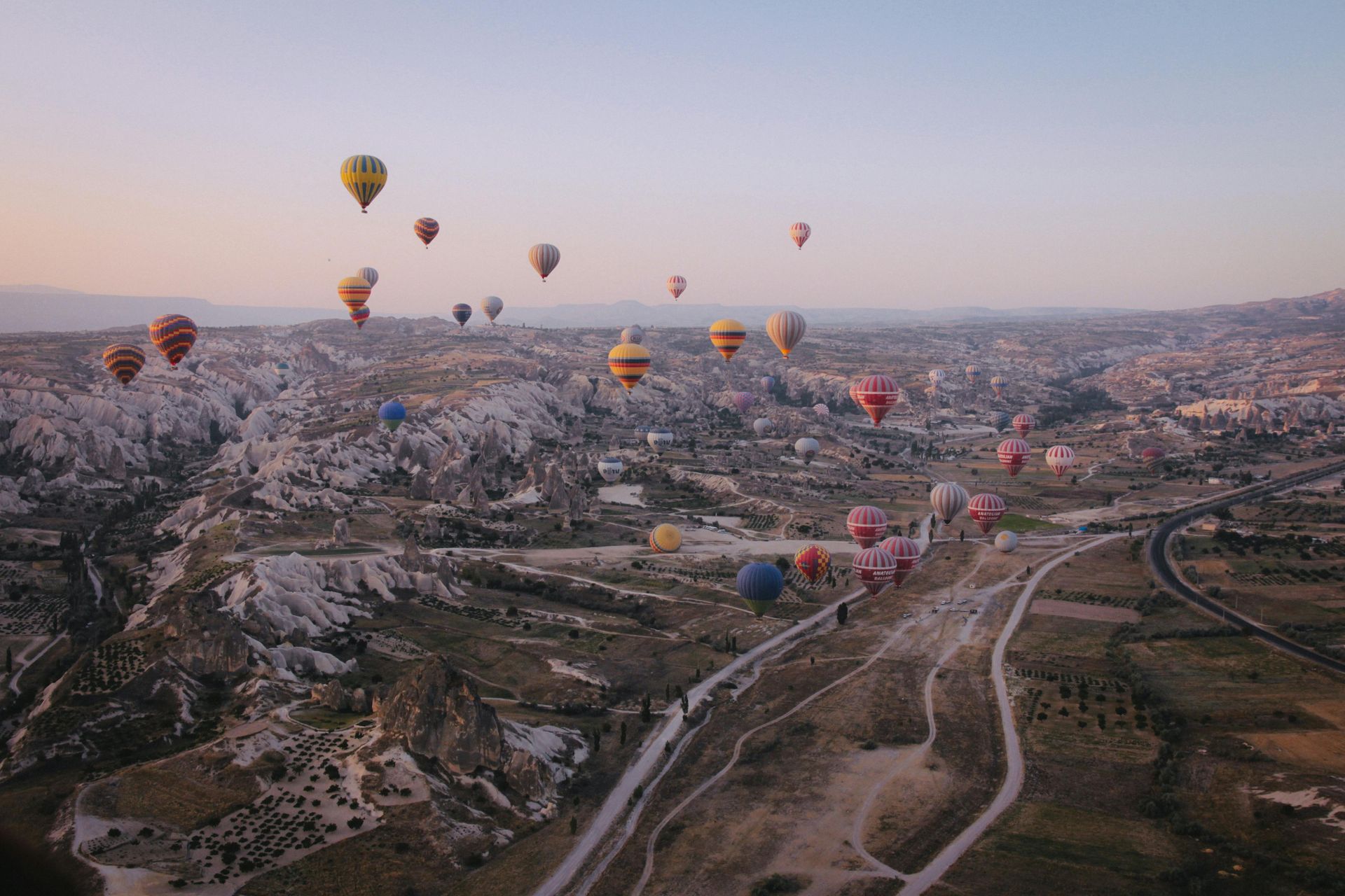 A bunch of hot air balloons are flying over a city.