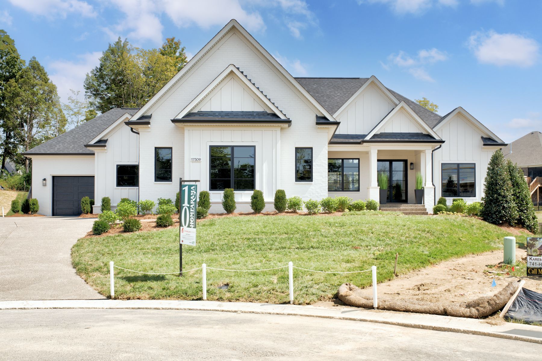 White house with black trim, black roof, and green lawn. Driveway on the left.