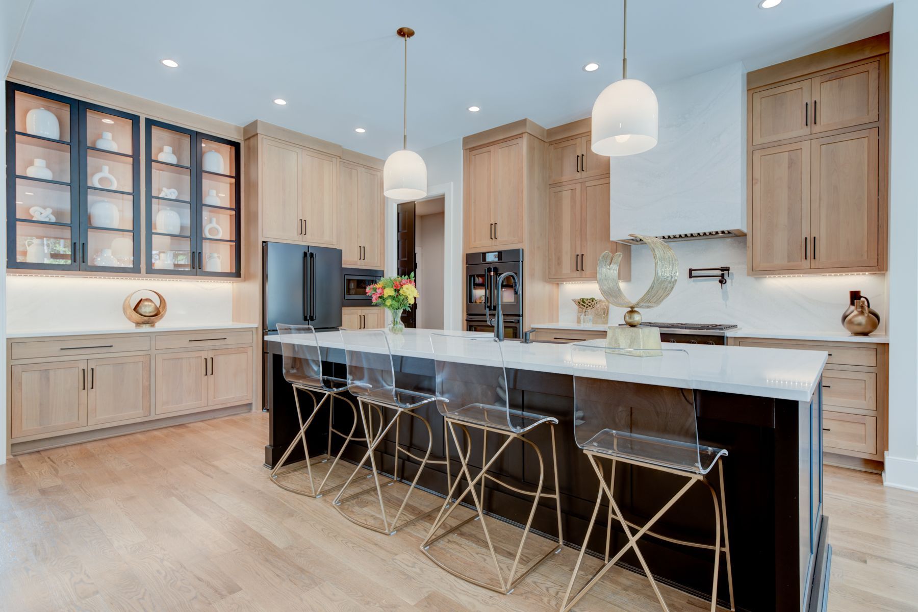 Modern kitchen with island, wooden cabinets, and clear acrylic stools.