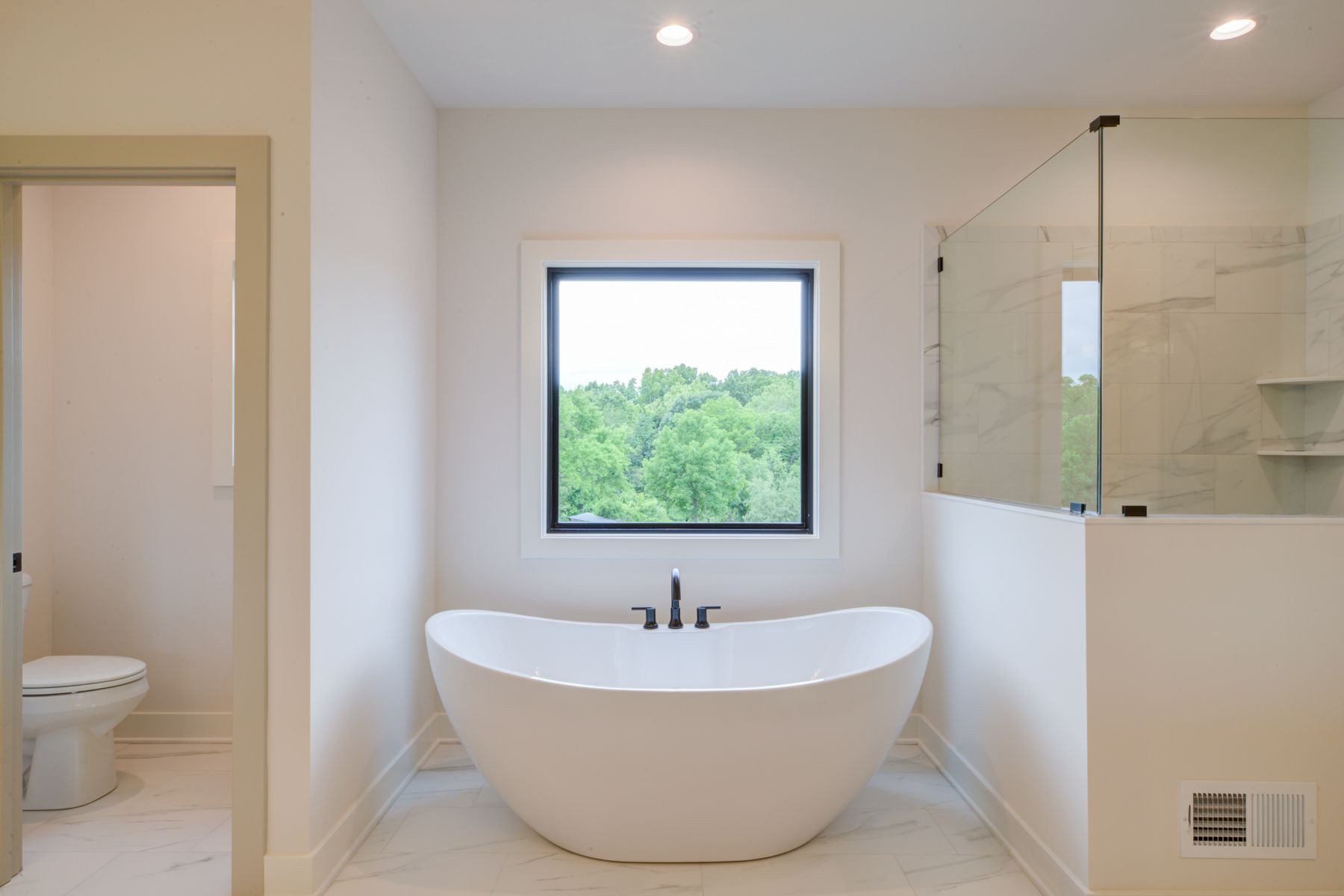 Modern bathroom with a white freestanding tub under a window.