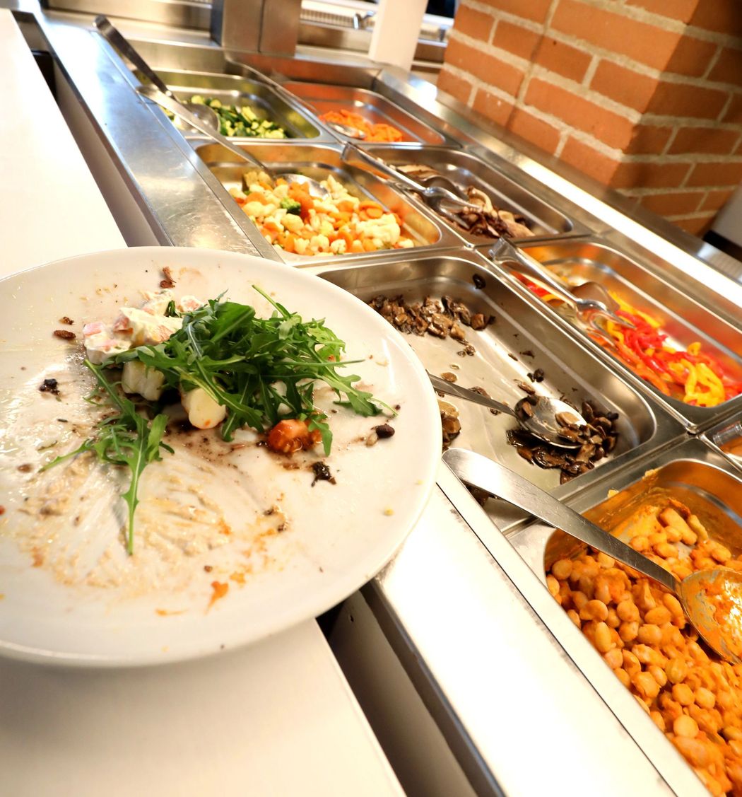 Un piatto di riso condito con erbe aromatiche accanto a un buffet di piatti caldi assortiti.