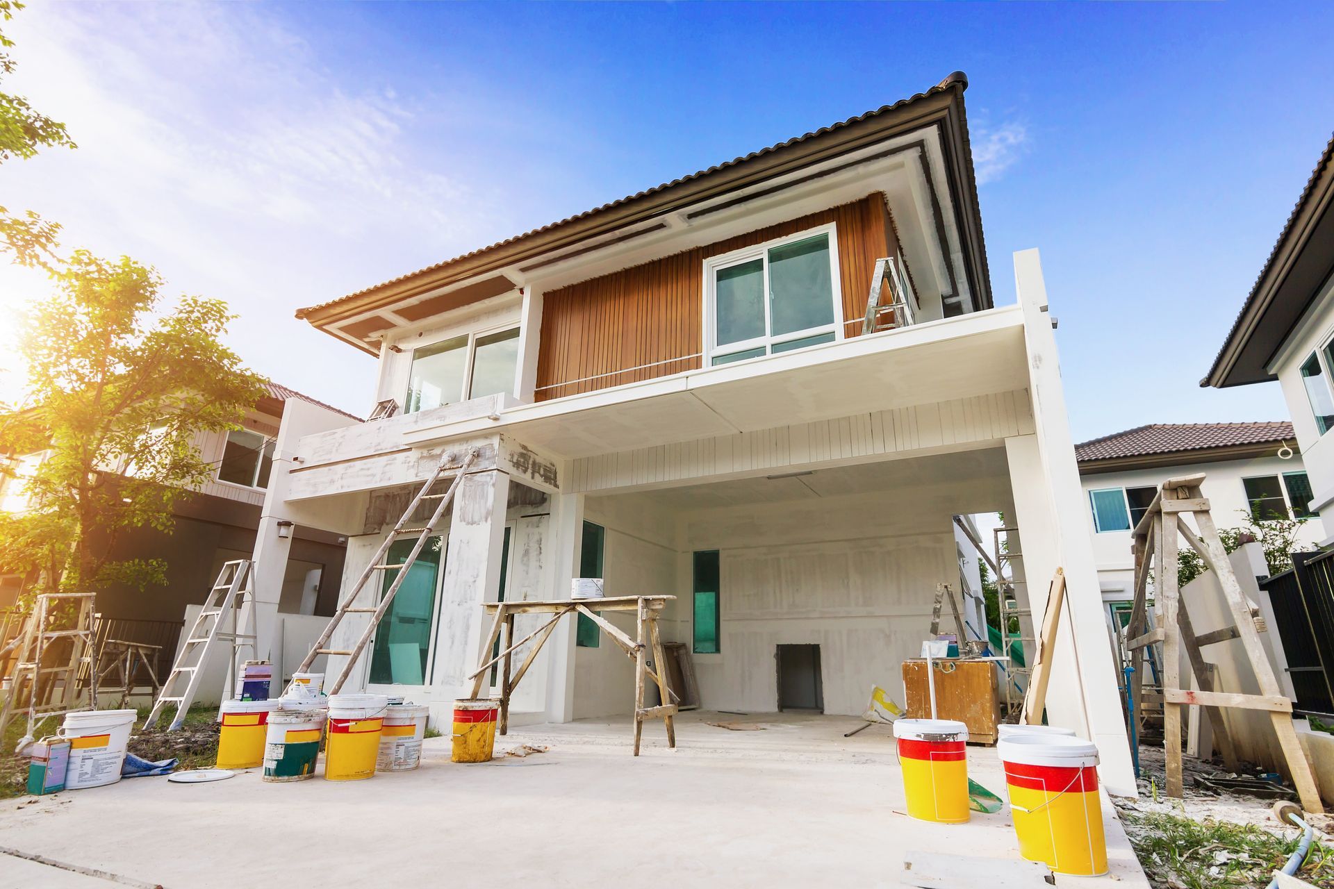Maison en construction, avec des pots de peinture, des échafaudages et la lumière du soleil.