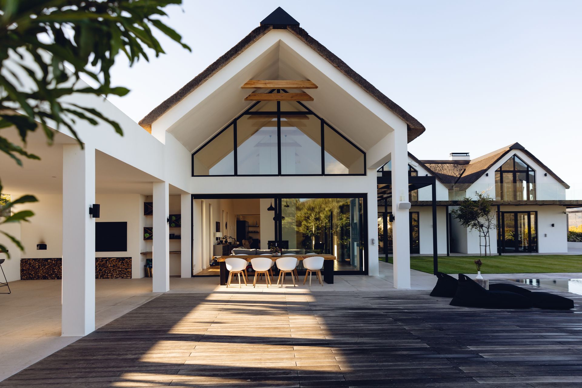 Une grande maison blanche avec une terrasse en bois devant.