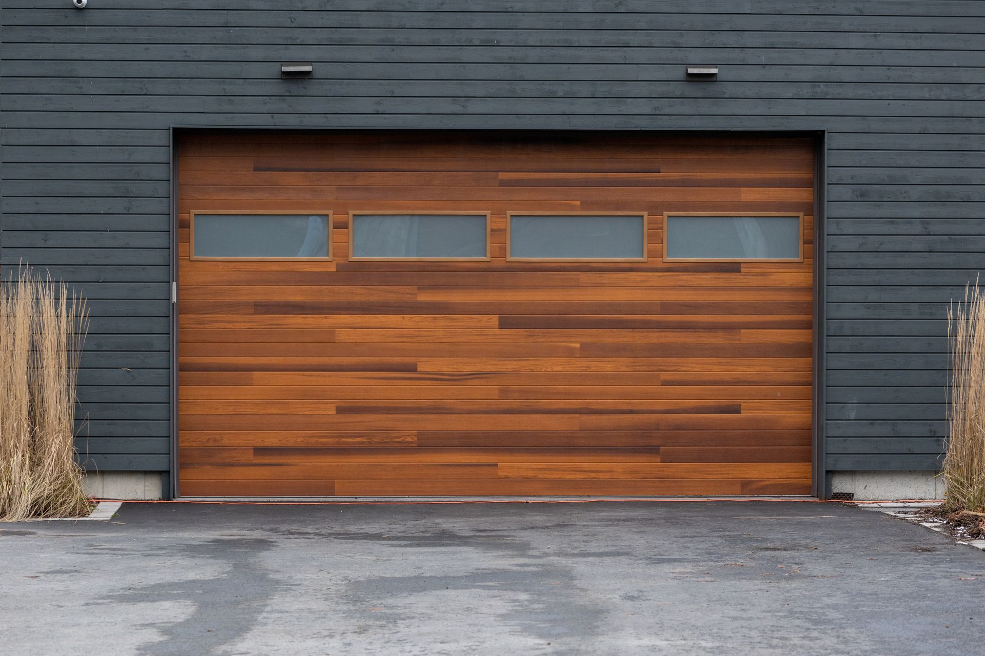 Une porte de garage en bois se trouve devant un bâtiment noir.