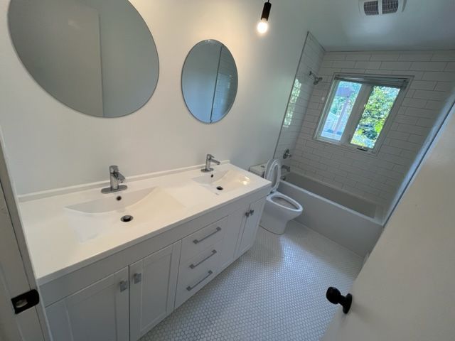 Une salle de bain avec deux lavabos, un WC et une baignoire.