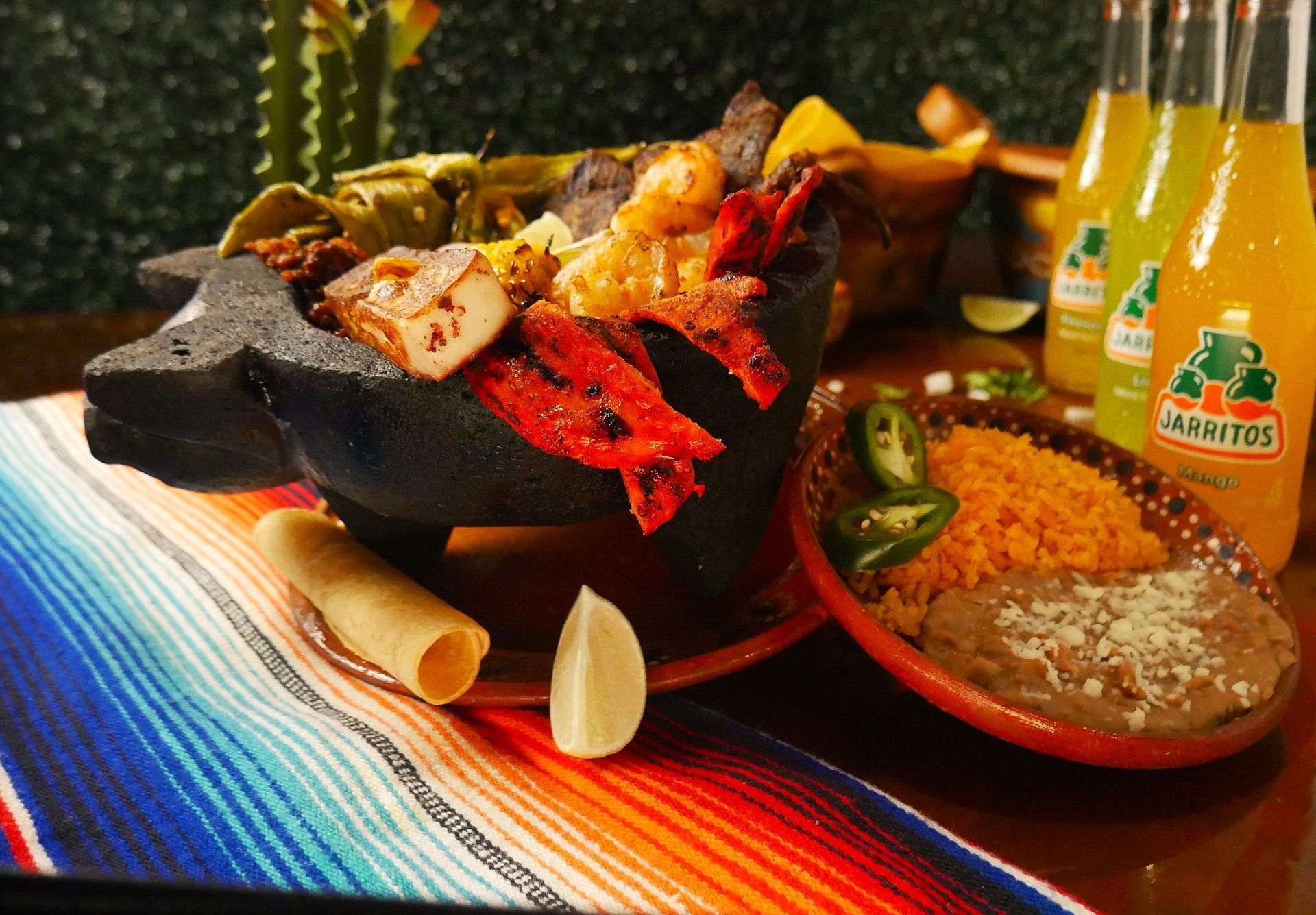 Sizzling volcanic stone molcajete loaded with grilled meats, seafood, and nopales - Taqueria El Chaparrito's signature dish