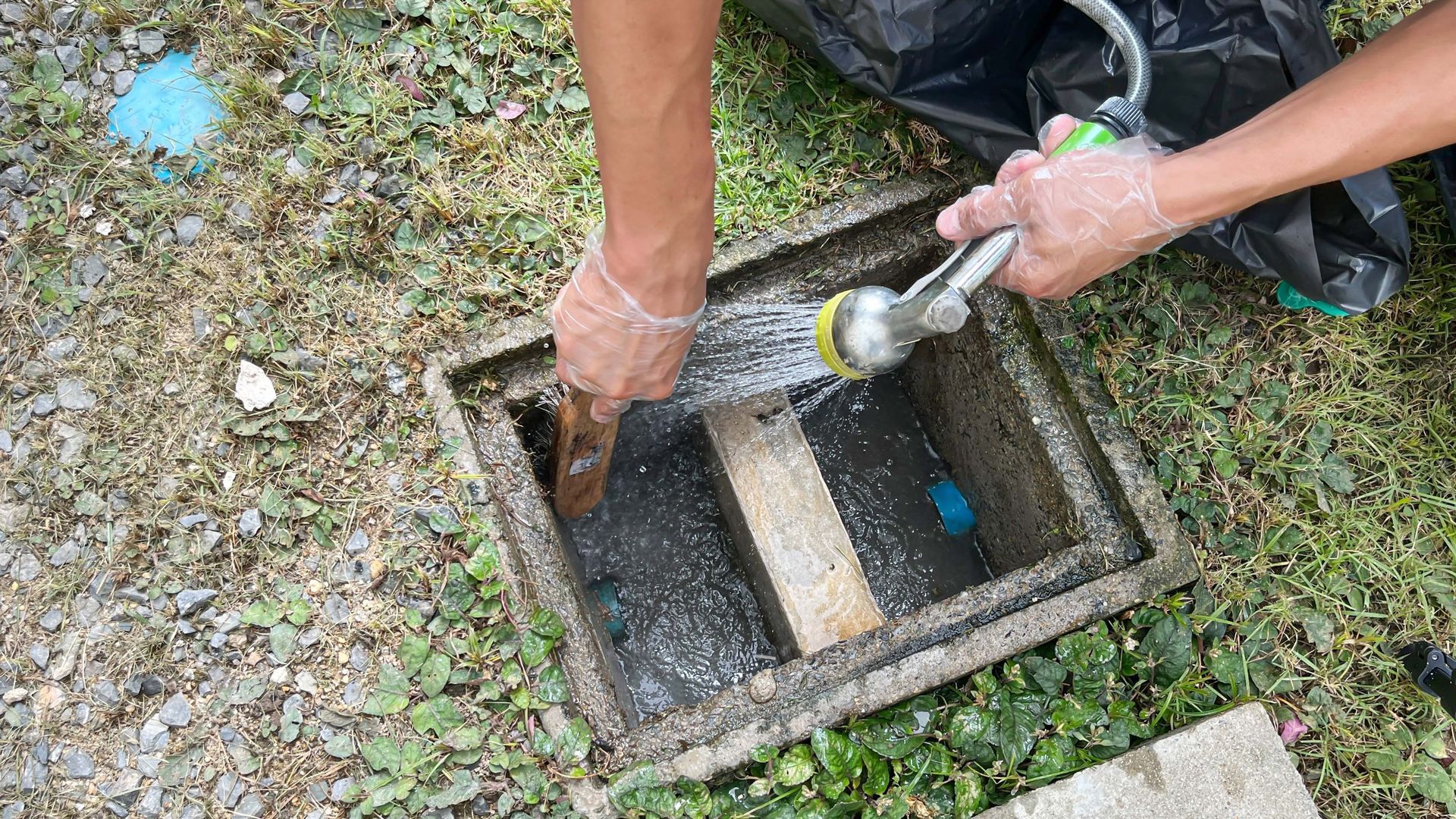 A person is cleaning a drain with a hose.