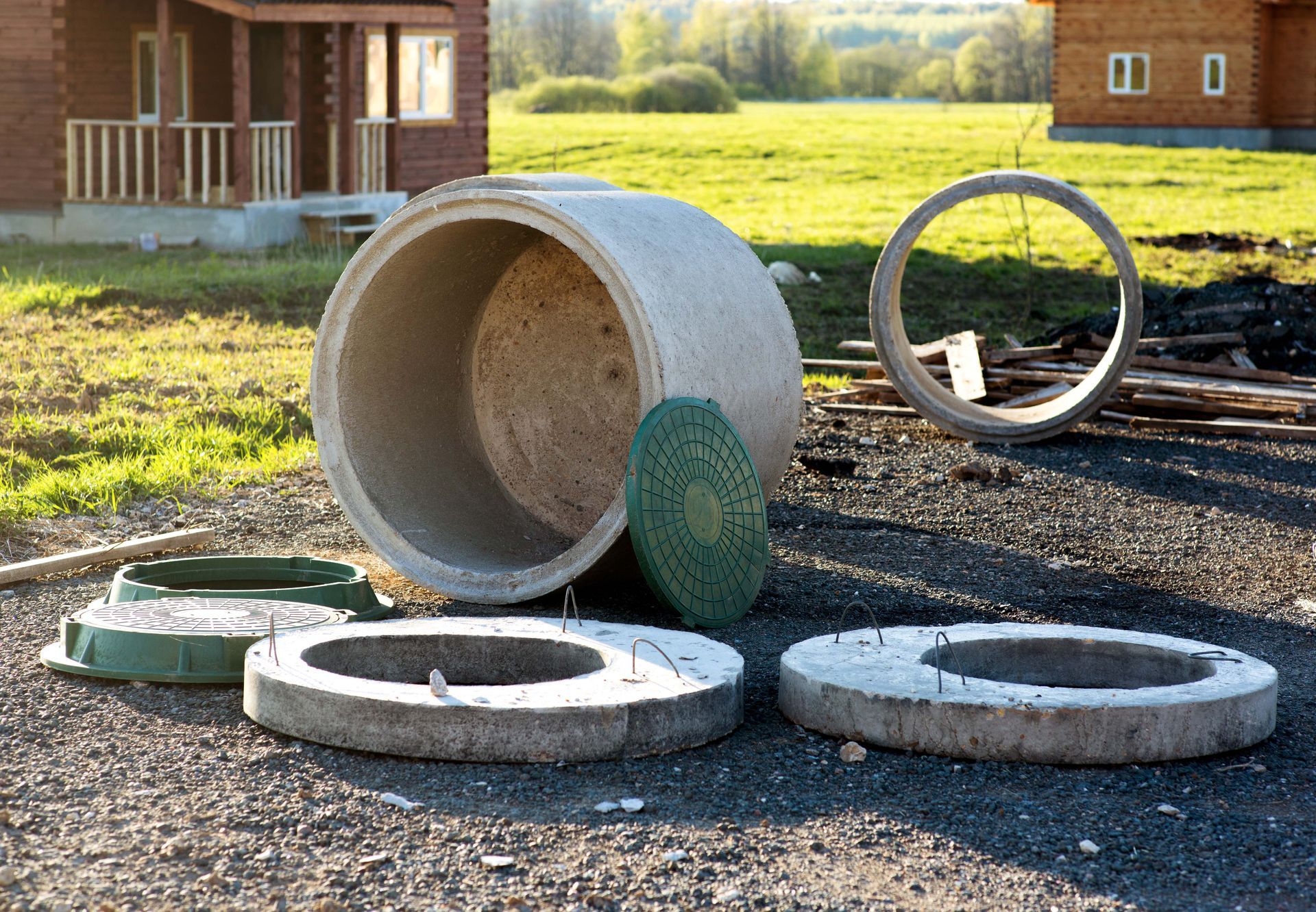 A bunch of concrete pipes are sitting on the ground in front of a house.