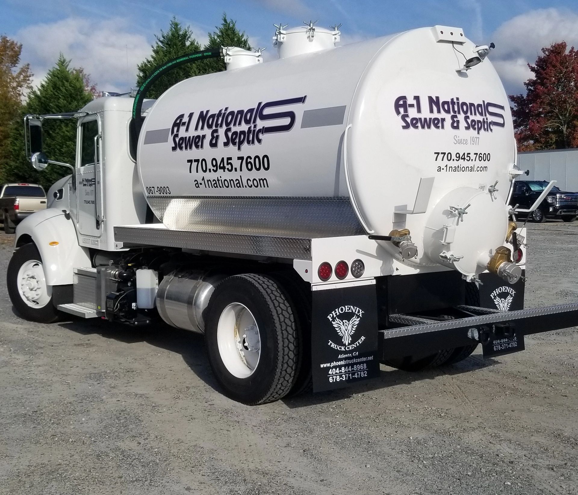 A national sewer & septic truck is parked in a gravel lot