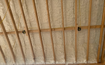 Spray foam insulation applied between wooden rafters in an unfinished attic space.