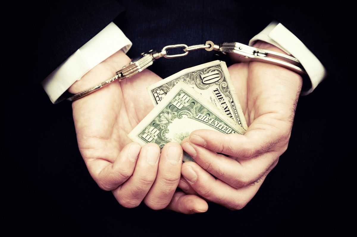 Businessman Hands in Handcuffs Holding Dollar Bill — Yuba City, CA — Law Office of Geoffrey J. Heitman