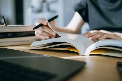 A person is writing in a notebook while sitting at a table.