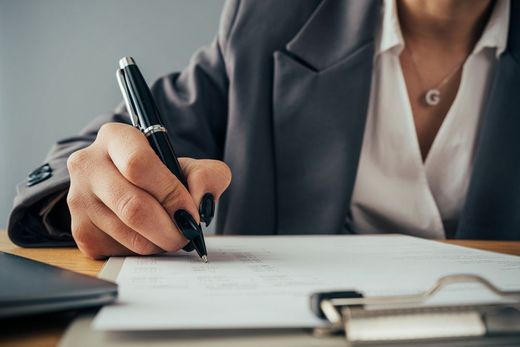 A woman is writing on a piece of paper with a pen.