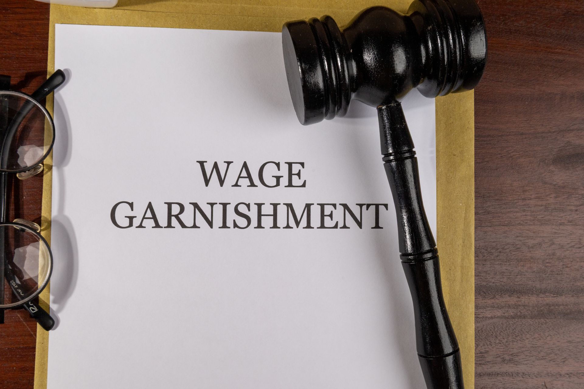 Gavel and wage garnishment document on desk with eyeglasses.