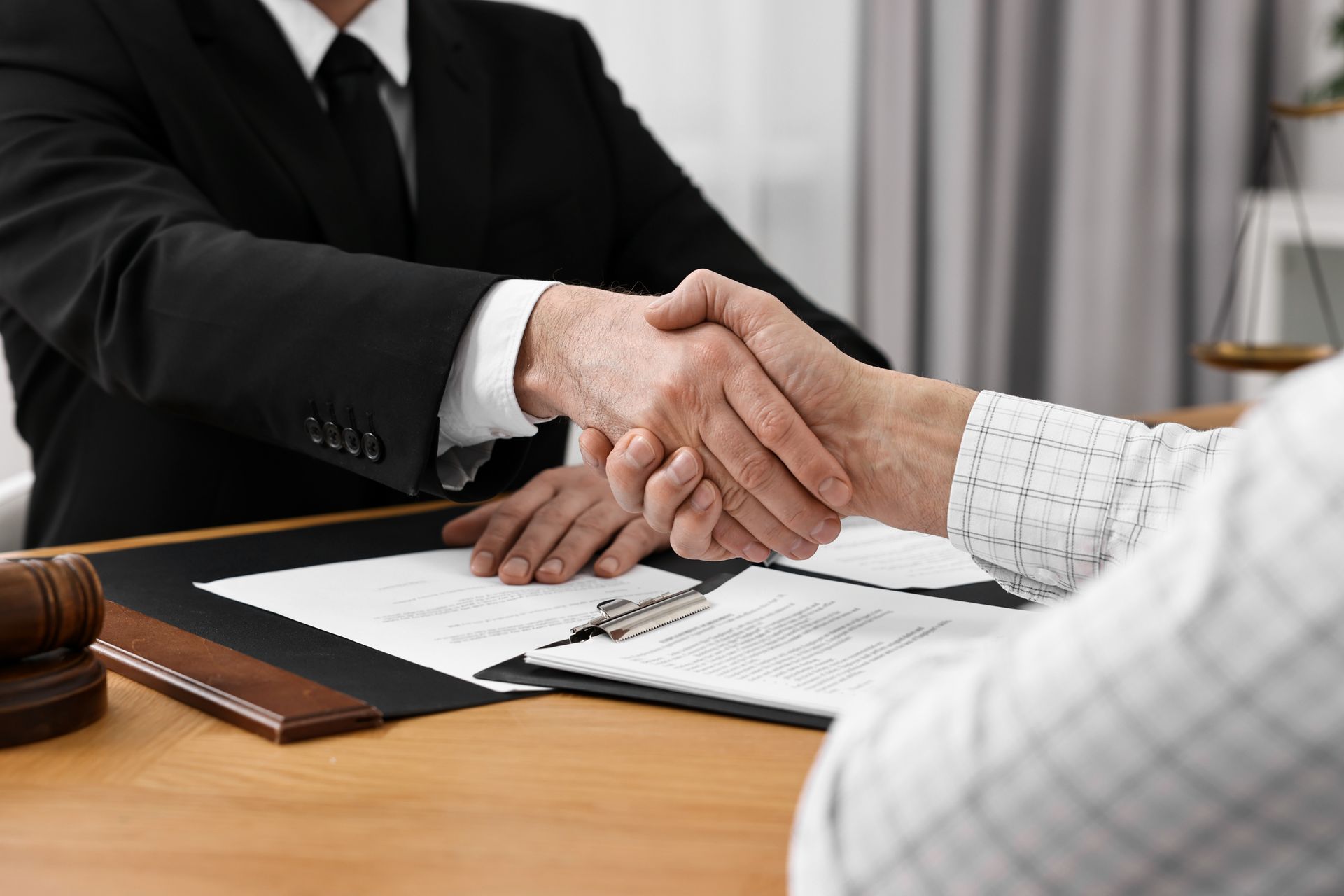 Close-up of a debt settlement attorney shaking hands with a client in an office.