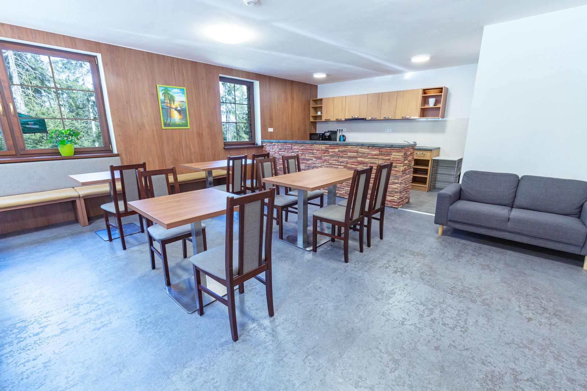 Obývacia izba so stolmi, stoličkami a pohovkou.