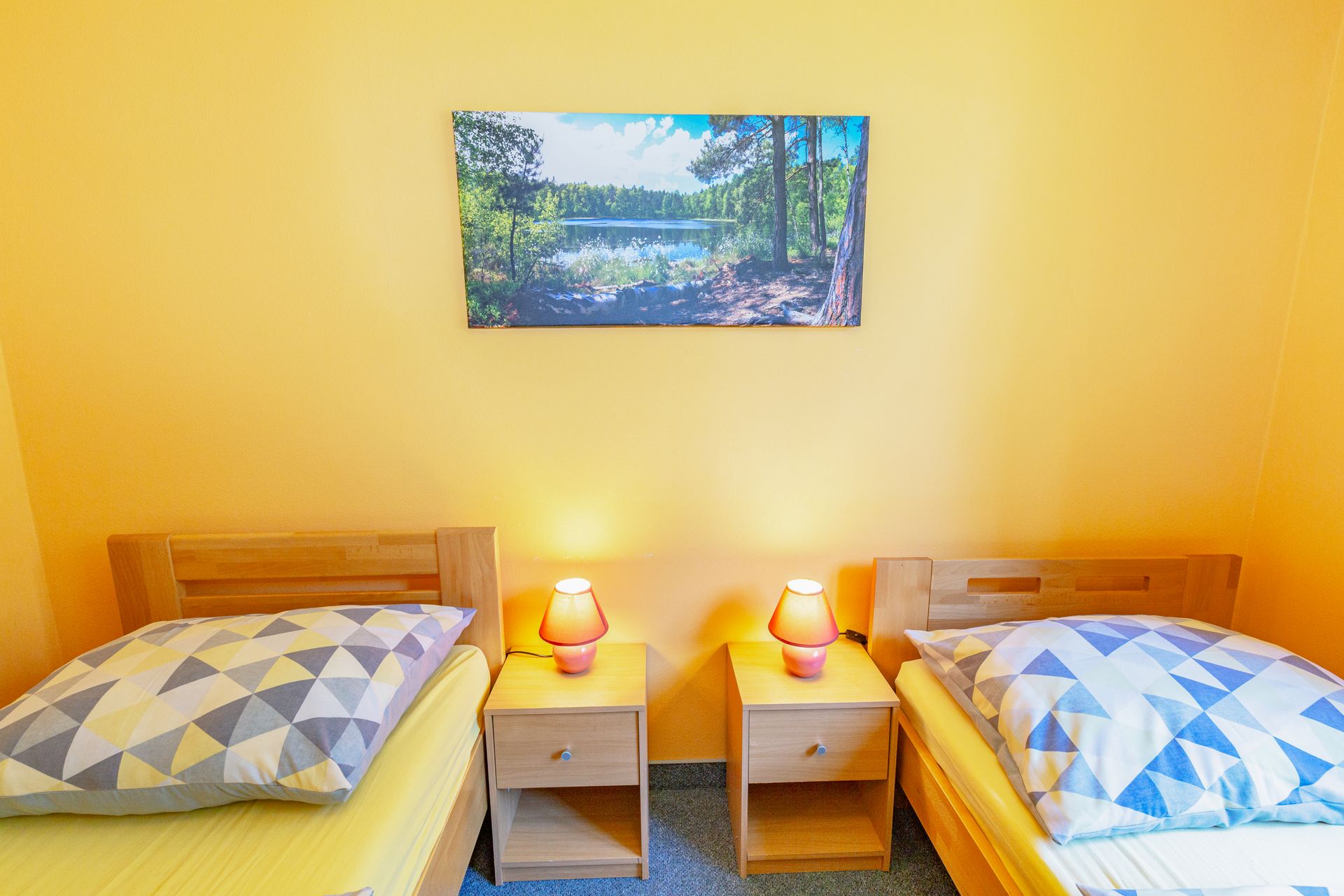 Spálňa s dvoma posteľami, dvoma nočnými stolíkmi a obrazom na stene.