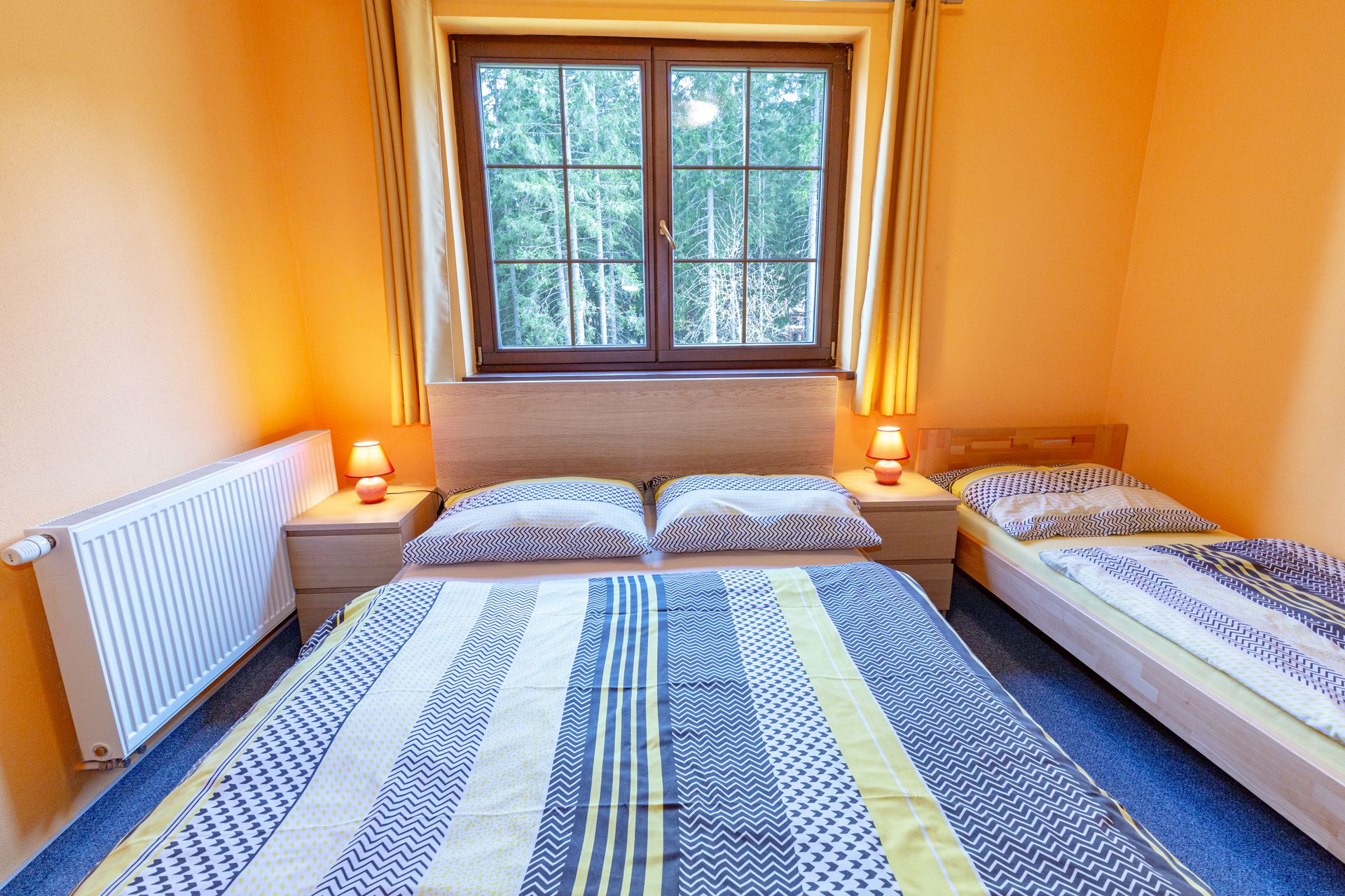 Spálňa s dvoma posteľami a veľkým oknom.