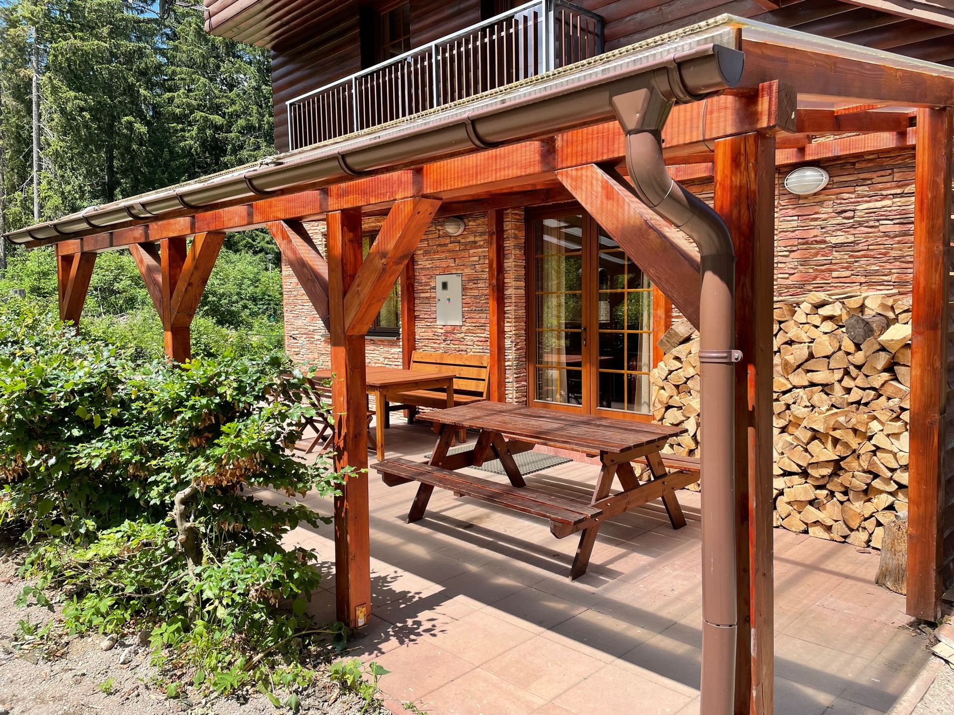 Drevená pergola s piknikovým stolom pod ňou.