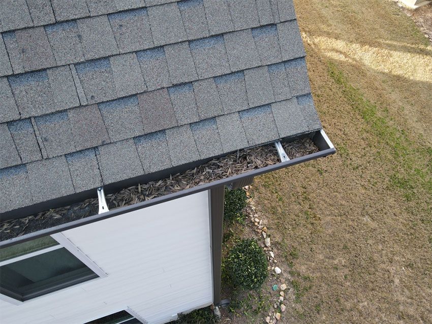 Roof gutter filled with leaves and debris on a house.