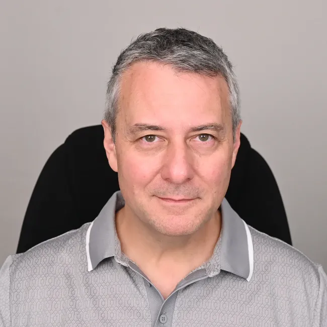 Portrait of a man in a gray polo shirt against a plain background