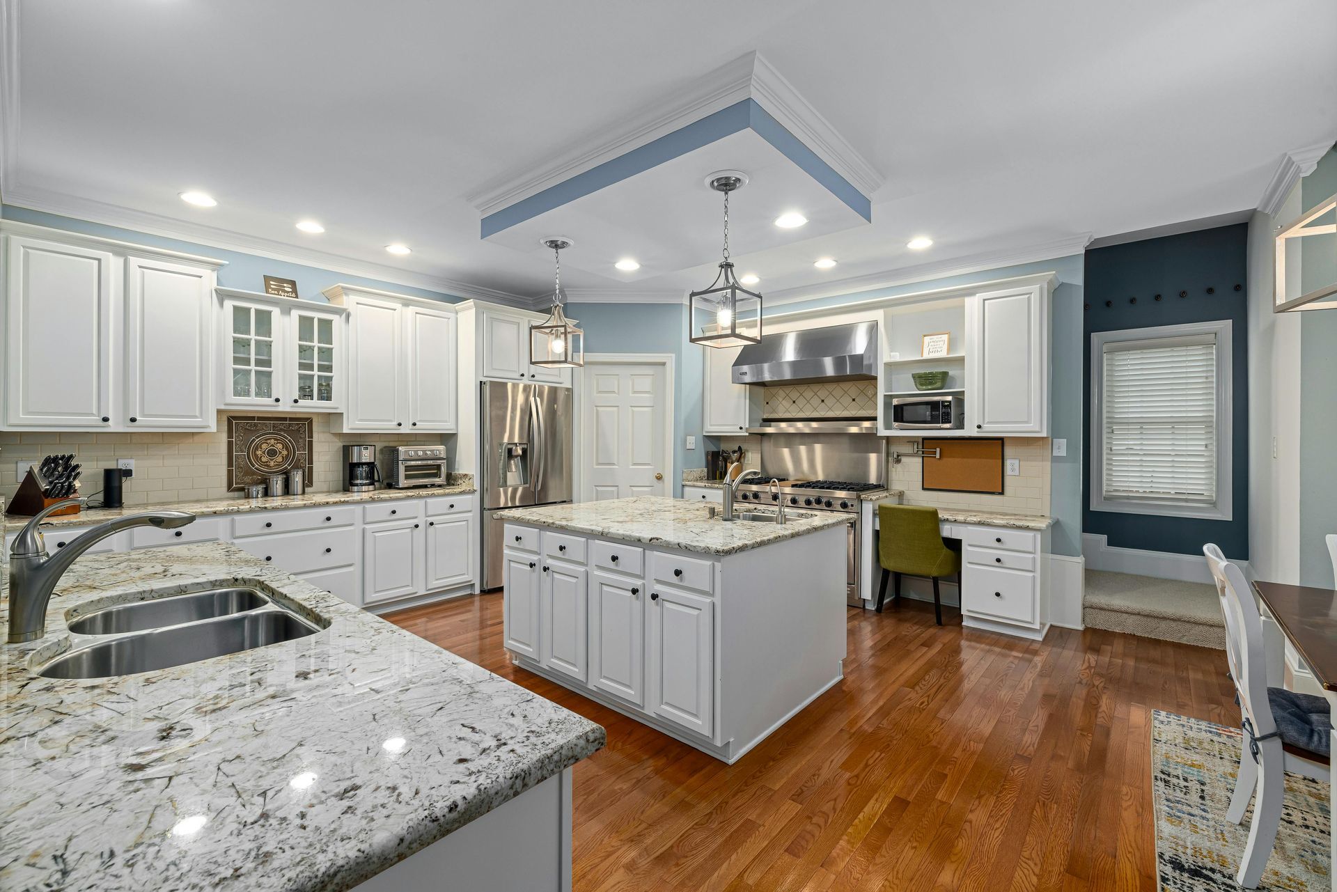 Modern kitchen with stainless appliances, white cabinets, black tile backsplash, and a breakfast bar with stools
