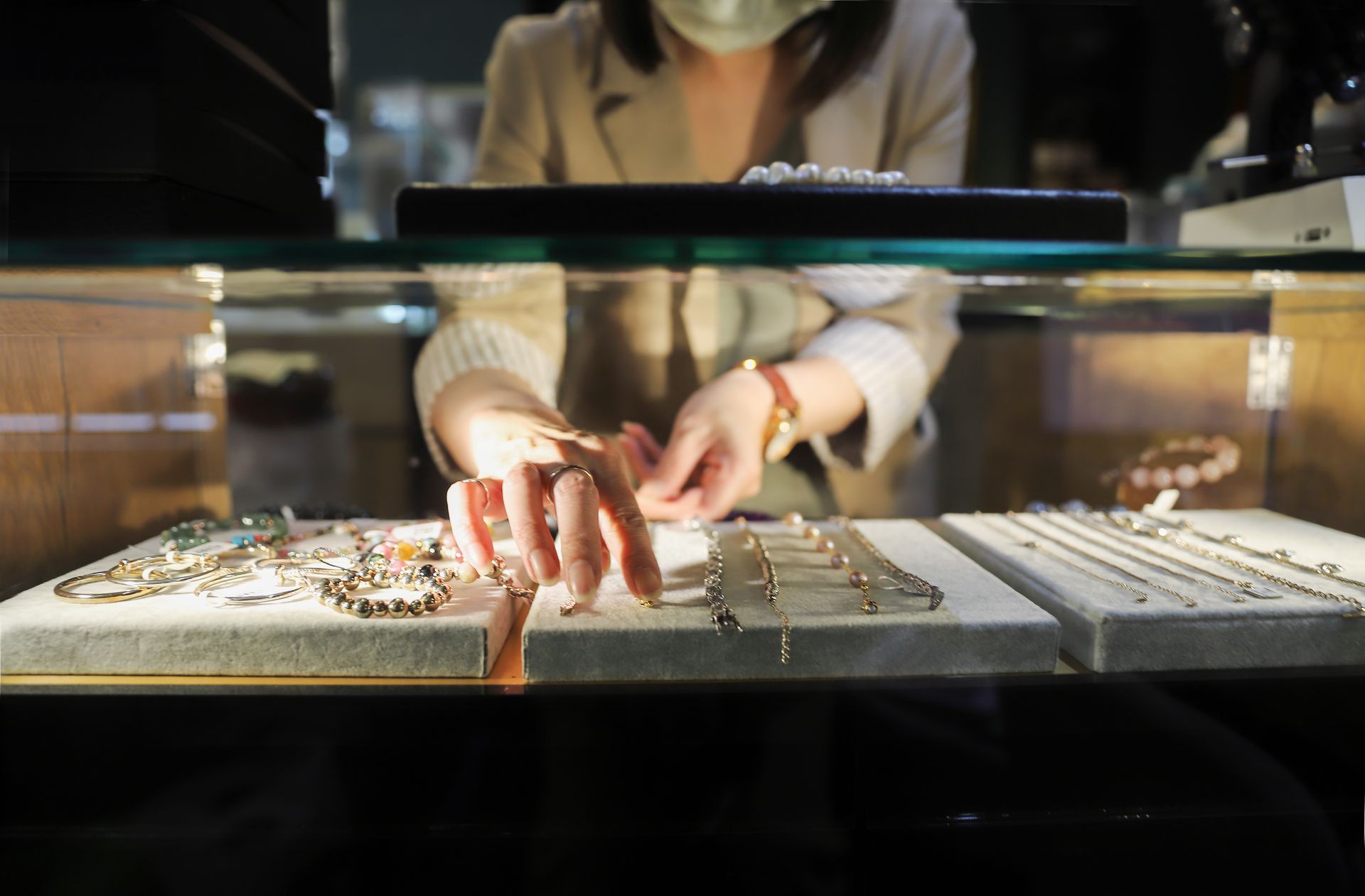 Une femme portant un masque regarde des bijoux dans un magasin.