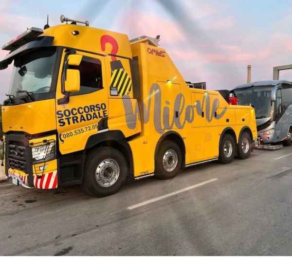 Yellow roadside assistance tow truck with “Dillo” branding parked on a road at sunset.