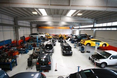 Classic and modern sports cars parked inside a large indoor garage.